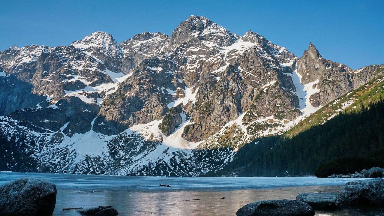 A mountain with snow on it and a lake in front under a blue sky