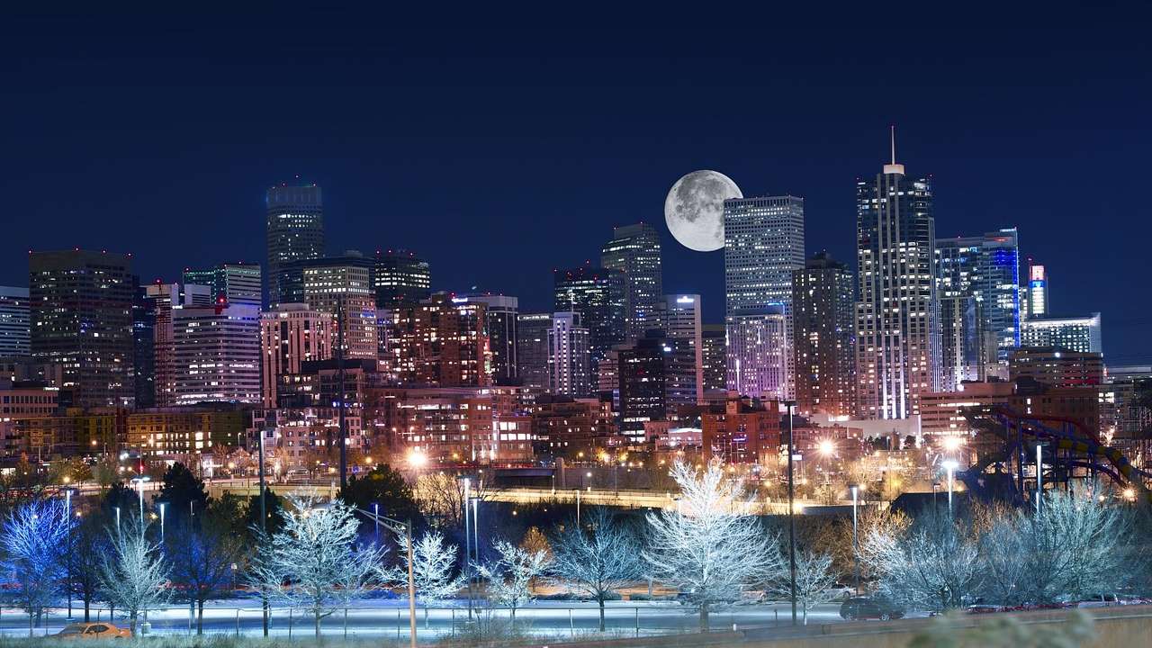 Buildings illuminated at night with a full moon in the sky