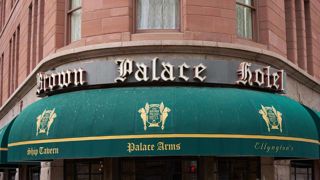 A hotel sign that says "Brown Palace Hotel" above a green awning