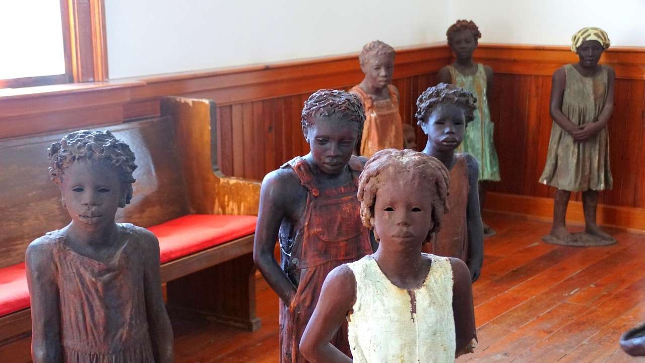 Statues of African American children inside a church with wooden flooring