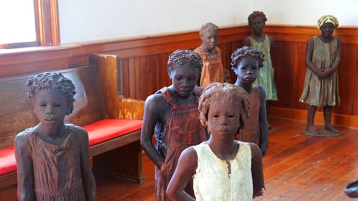 Statues of African American children inside a church with wooden flooring