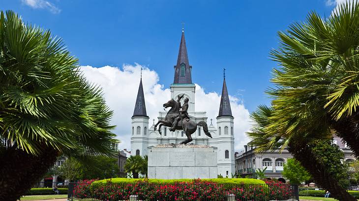 A garden with a horse statue and a castle-style cathedral in the background