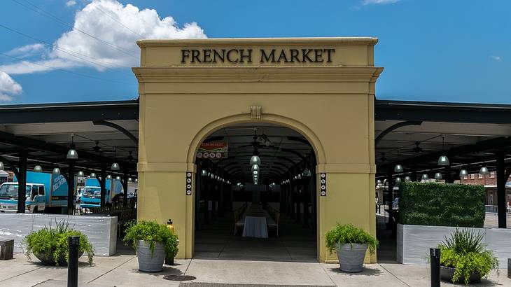 A large entryway arch that says French Market with path and plants in front