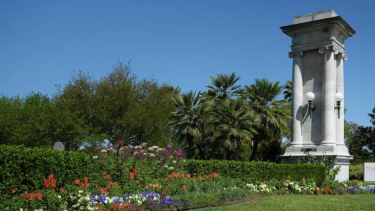 A garden with grass, trees, and flowers, and a white stone statue