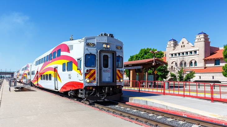 A colorful train near a waiting shed and an old building