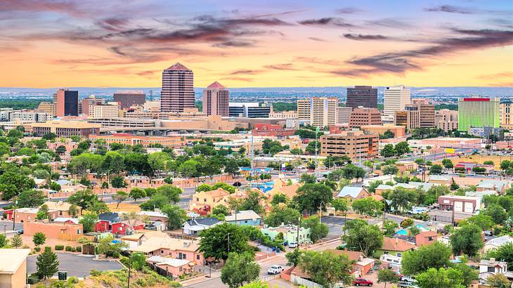 An aerial shot of a city under an orange and purple sky at sunset