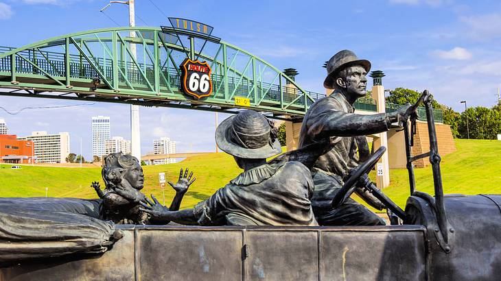Bronze statues of men with a road entrance archway at the back saying "Route 66"