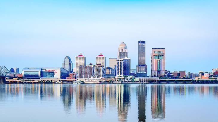 A city skyline with its reflection on a body of water under a blue and purple sky