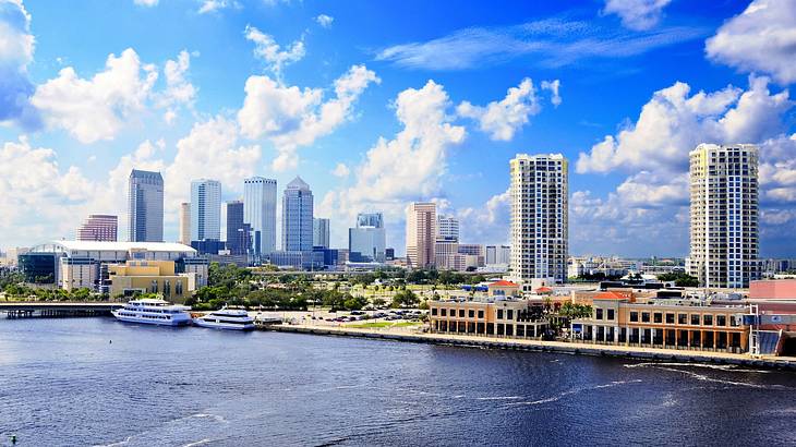 A city skyline next to the water under a blue sky with white clouds