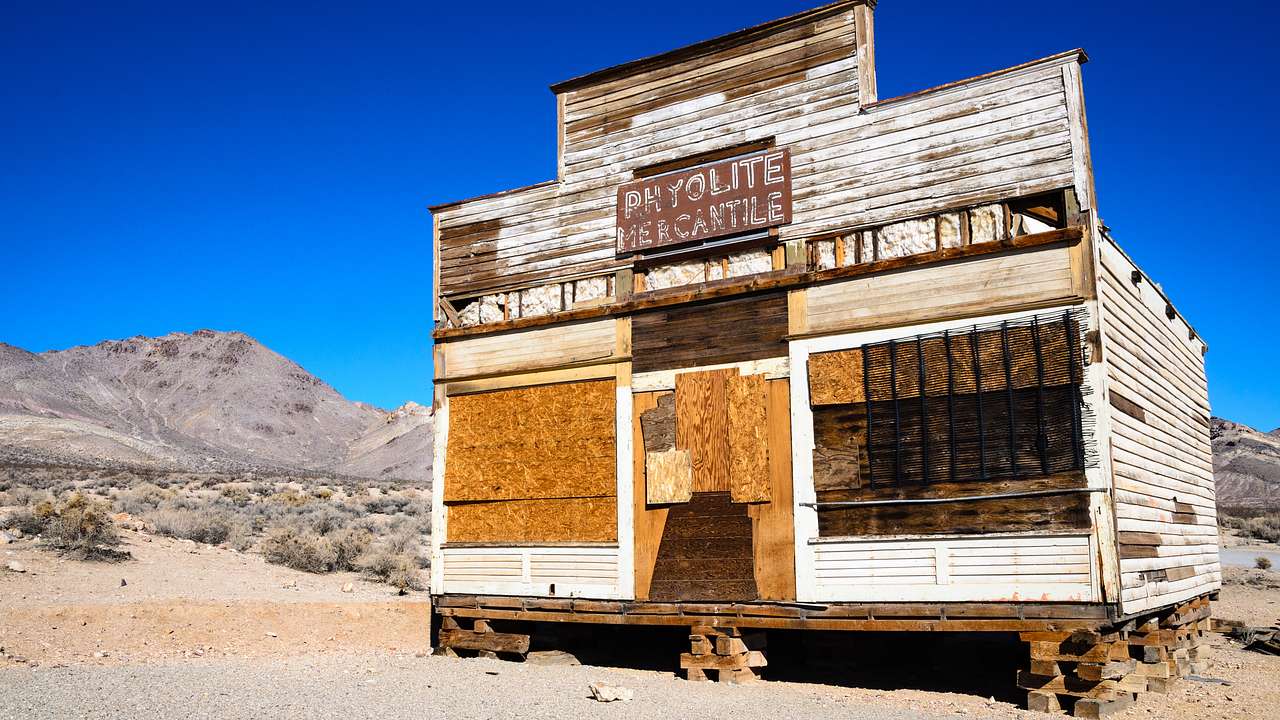 An old wooden building in the middle of the desert under a clear blue sky