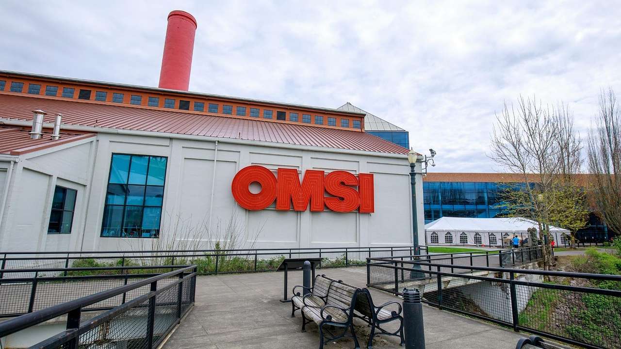 A white building with a red chimney and a red OMSI sign