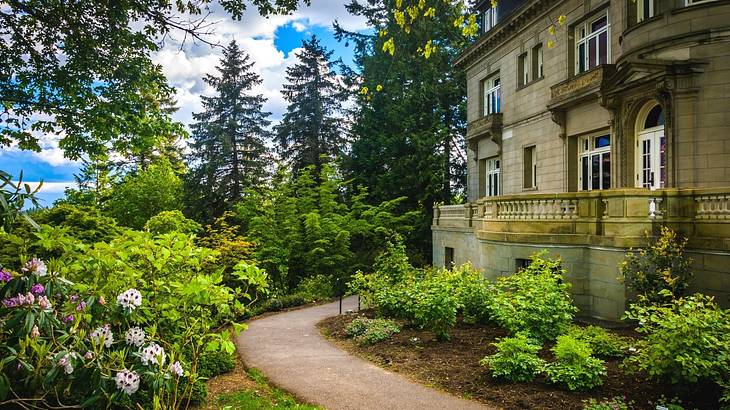 A path going through a garden with a mansion to the side