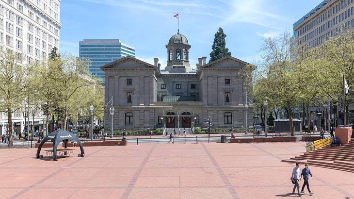 A square with a stone building with a dome in the middle on a clear day