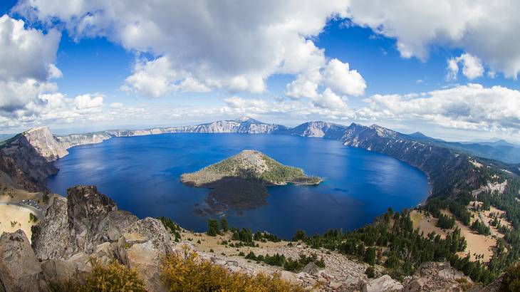 An islet in the middle of a volcanic crater lake under a blue sky with clouds
