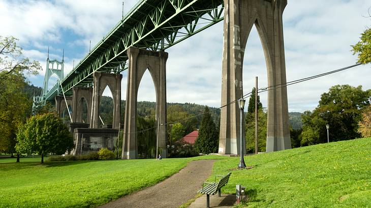 A landscaped area with a bench under a bridge