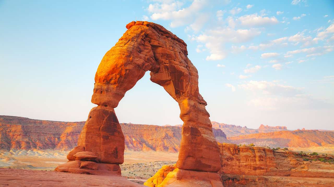 Facts about Utah state -
red sandstone arch next to landscape of red rock mountains