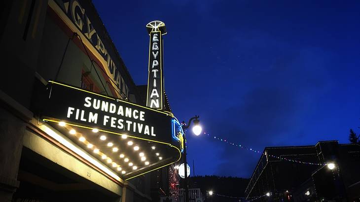 The exterior of a vintage theater with an illuminated "Sundance Film Festival" sign