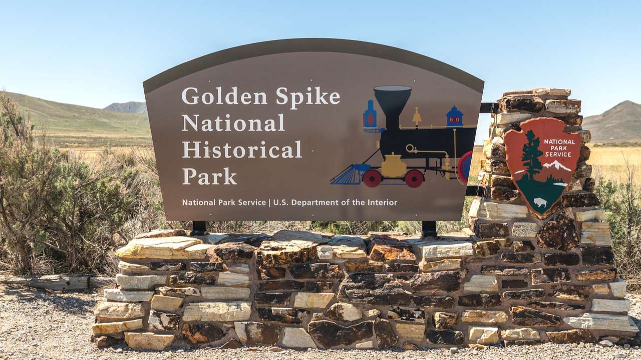 A sign with a train symbol that says "Golden Spike National Historical Park"