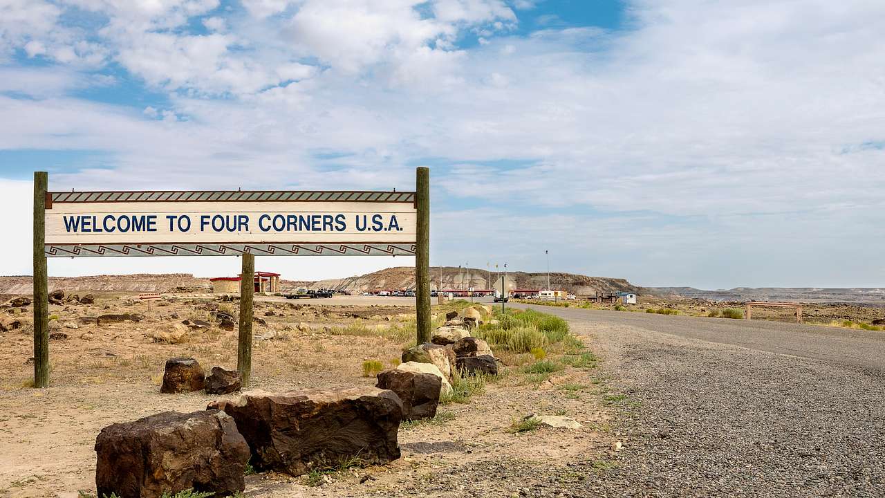 A sign that says "Welcome to Four Corners U.S.A" next to a road