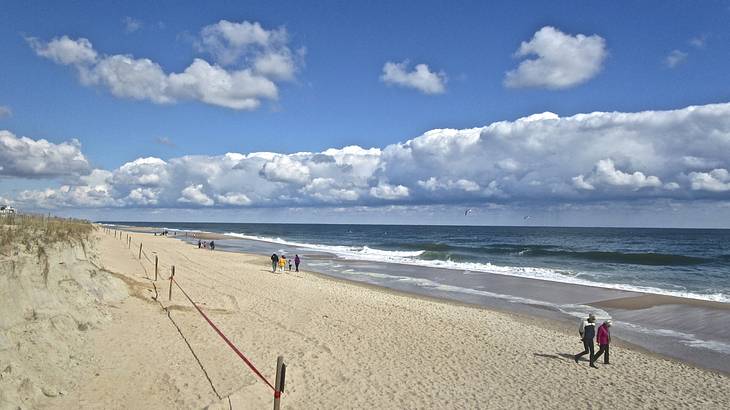 A sandy beach with people walking on it next to the ocean