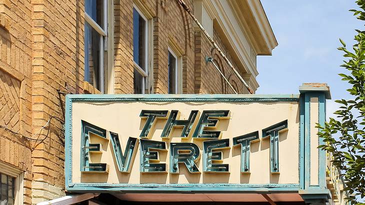 A beige sign with a green border that says "The Everett" in green