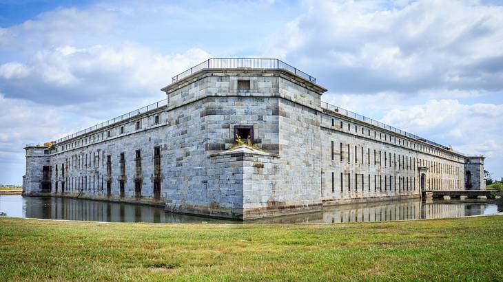 A stone fort structure with a moat around it next to green grass