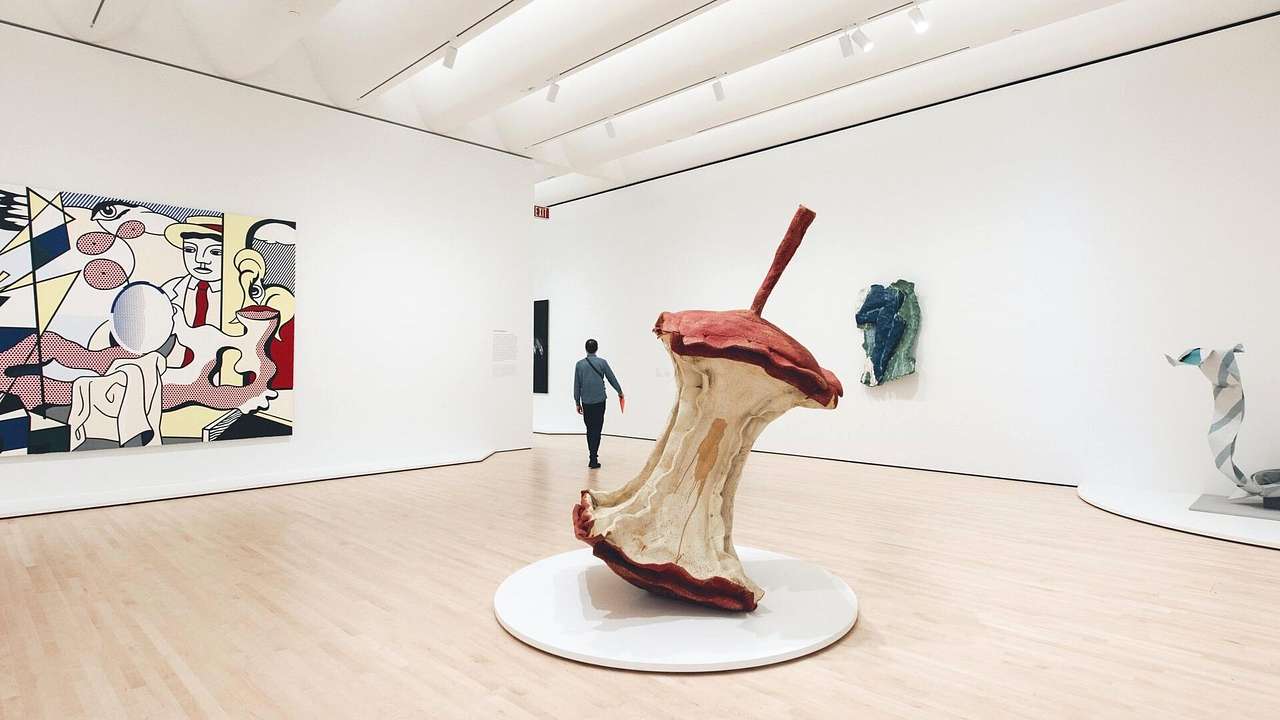 The interior of an art gallery with an apple core sculpture and modern art paintings