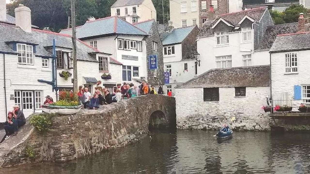 People sitting on a stone ledge above water with white houses around