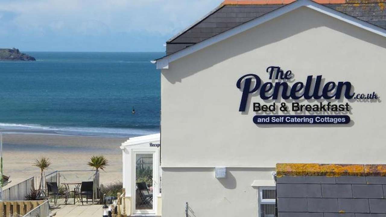 The outside of a white building with a sign overlooking a beach