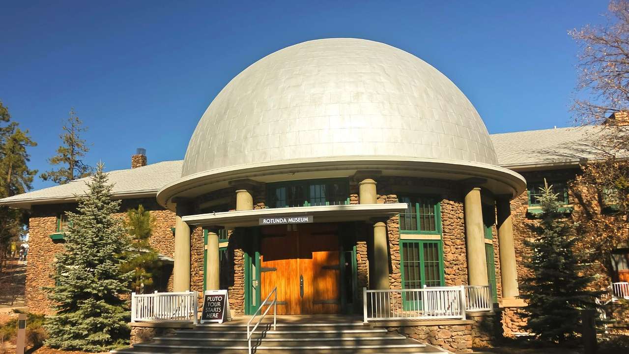 A museum building with a round dome-like gray roof under a clear sky