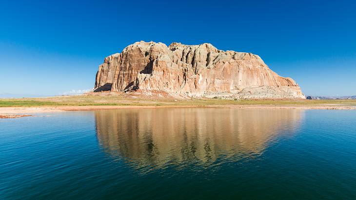 A rugged white canyon surrounded by a blue lake under a clear sky