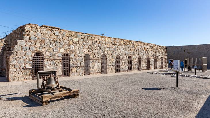 A stone building with lined up arched prison cell doors on a sunny day