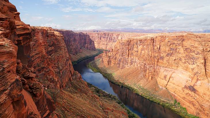 A shallow river winding through a gorge under a cloudy sky