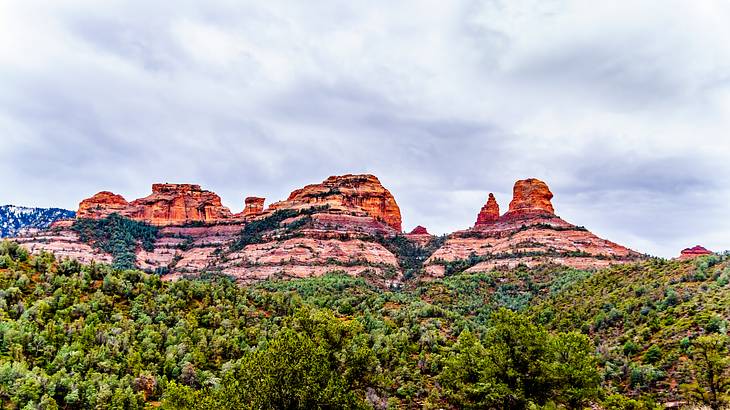Large red rocks surrounded by a green trees under a cloudy sky