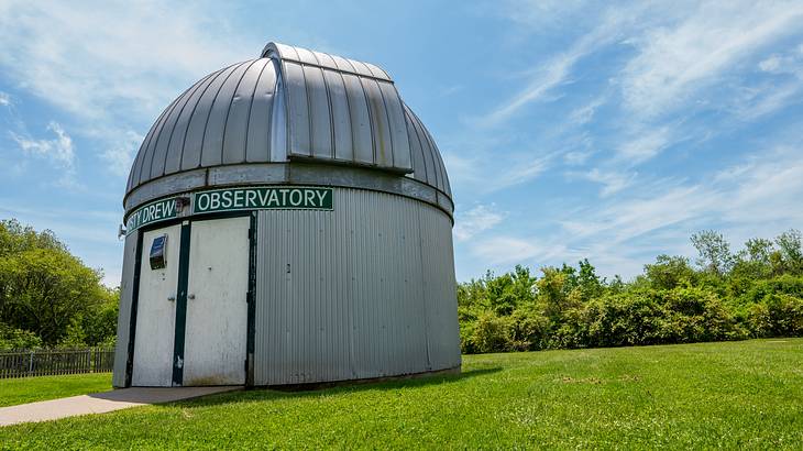 A silver-grey domed building with an observatory sign sitting on the grass