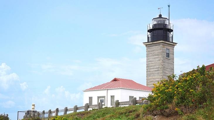 A lighthouse with a smaller white and red building next to it under a blue sky