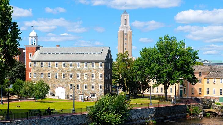 An old-fashioned stone building and tower in a small town by a river