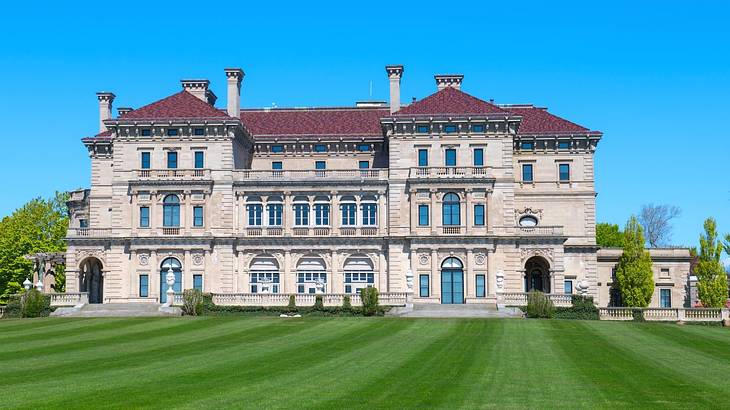 A luxury mansion with a green lawn in front of it under a clear blue sky