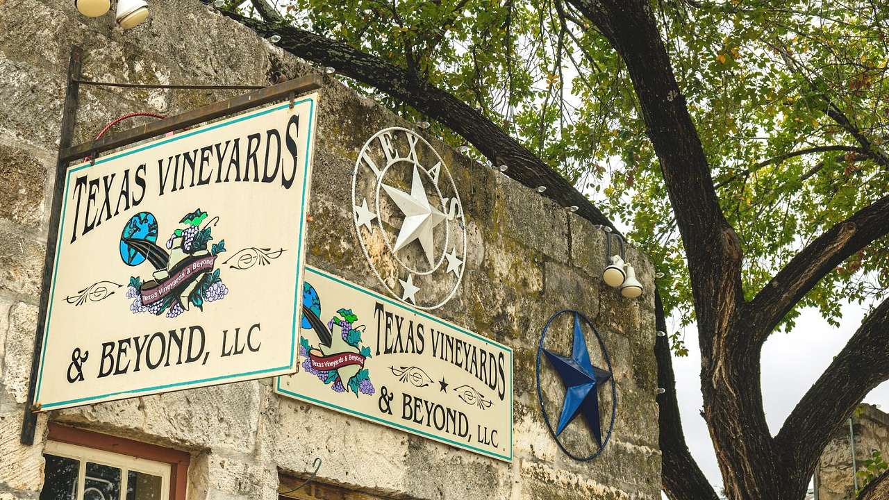 A stone building with signs that say "Texas Vineyards & Beyond, LLC"