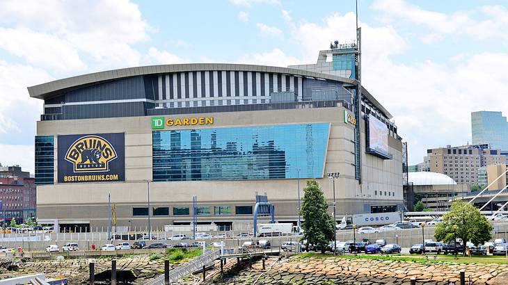 A large building with glass panels and a sign saying "TD Garden" near roads and cars