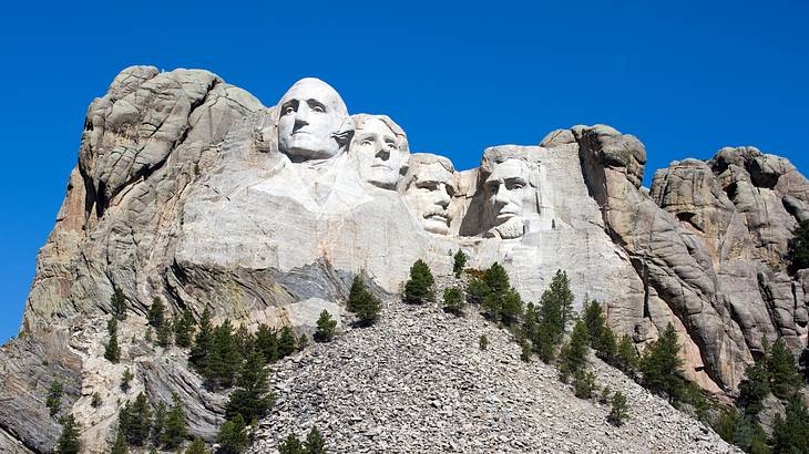 The faces of four people carved into the cliff of a rocky mountain