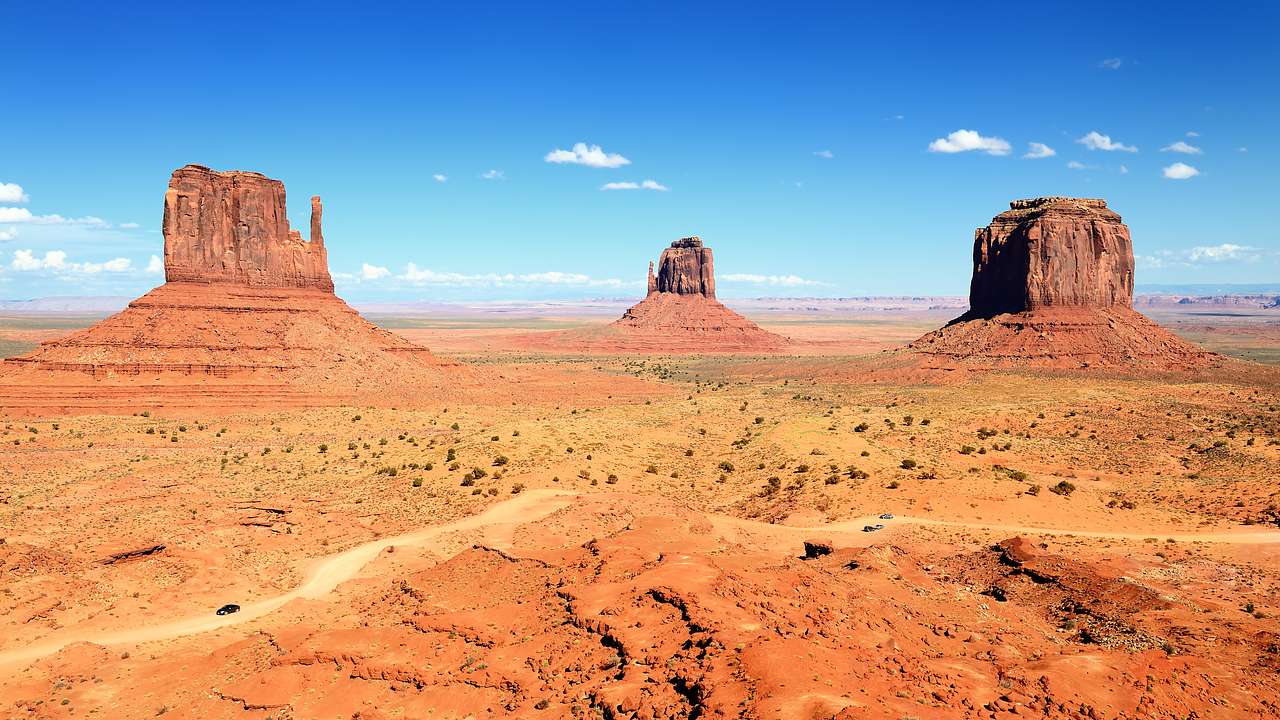 Three red sandstone formations in the middle of a desert