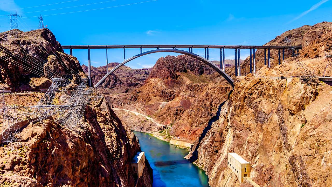 A steel arch bridge connecting 2 sides of a canyon with a river running through it