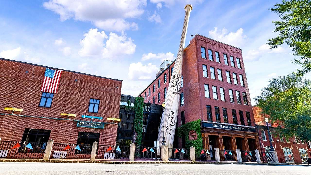 A tall red brick building with a giant baseball bat resting on it