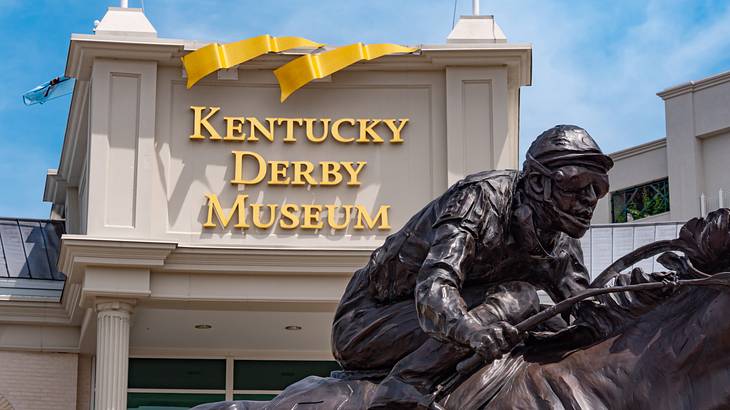 A statue of a horse rider against a building with a "Kentucky Derby Museum" sign
