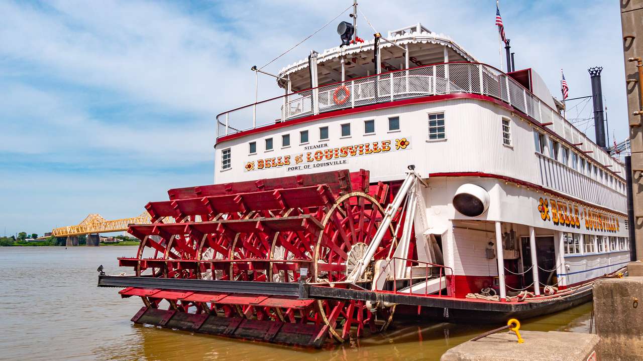 A white paddle steamer with red wheels on a river