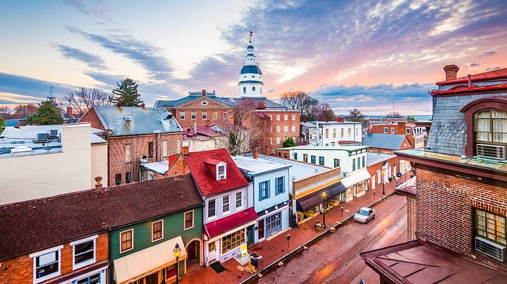 A city with small brick buildings and a building with a white dome at sunset