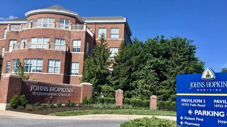 A brick building with a John Hopkins sign next to a blue sign and green trees
