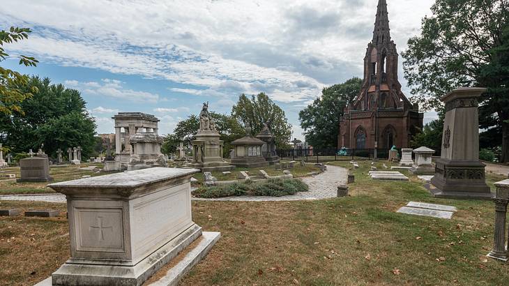 A cemetery with tombs and gravestones surrounded by grass and trees