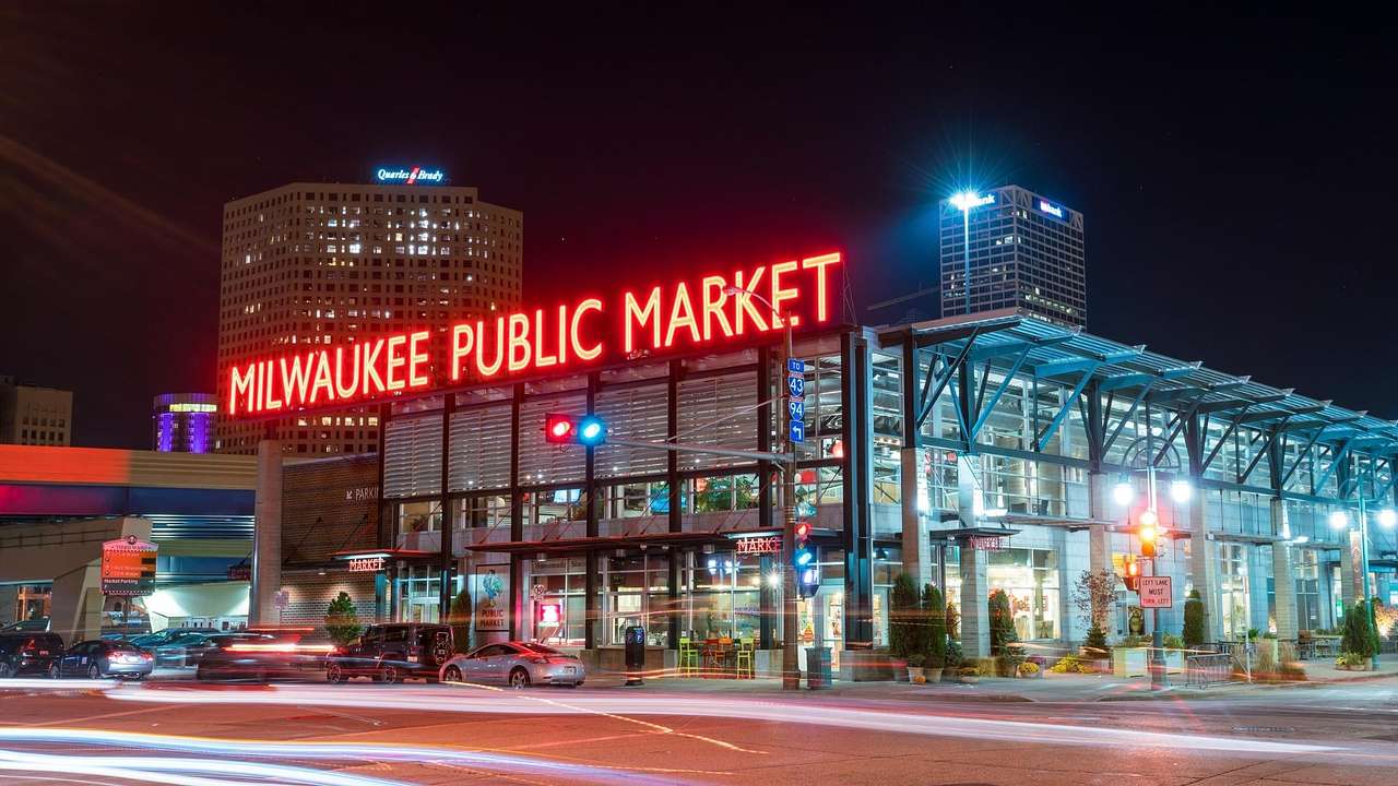 A glass building with a red neon sign that says "Milwaukee Public Market"